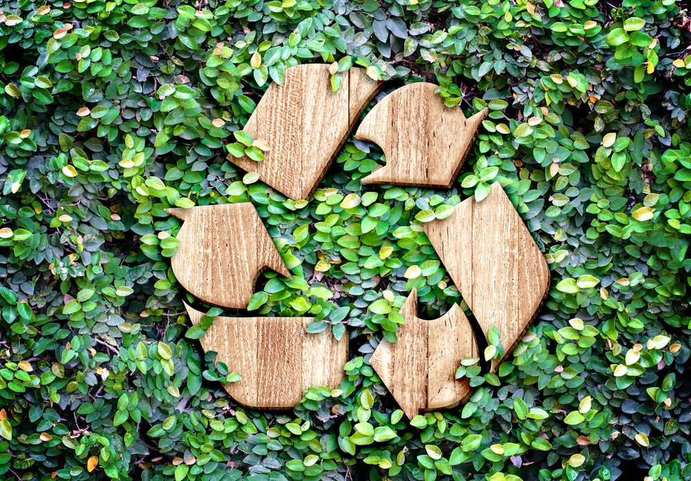 Recycling symbol shown surrounded by green bushes to represent easy ways to green up your office with business electronic recycling, server recycling, and more